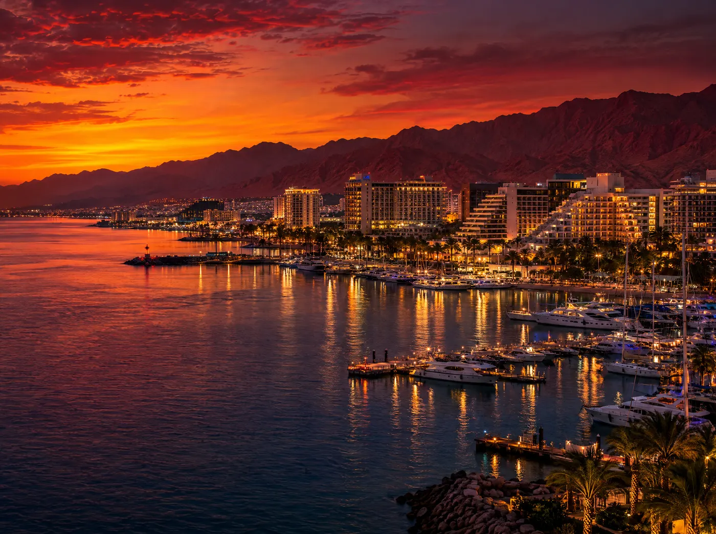Eilat marina at sunset with red desert mountains behind